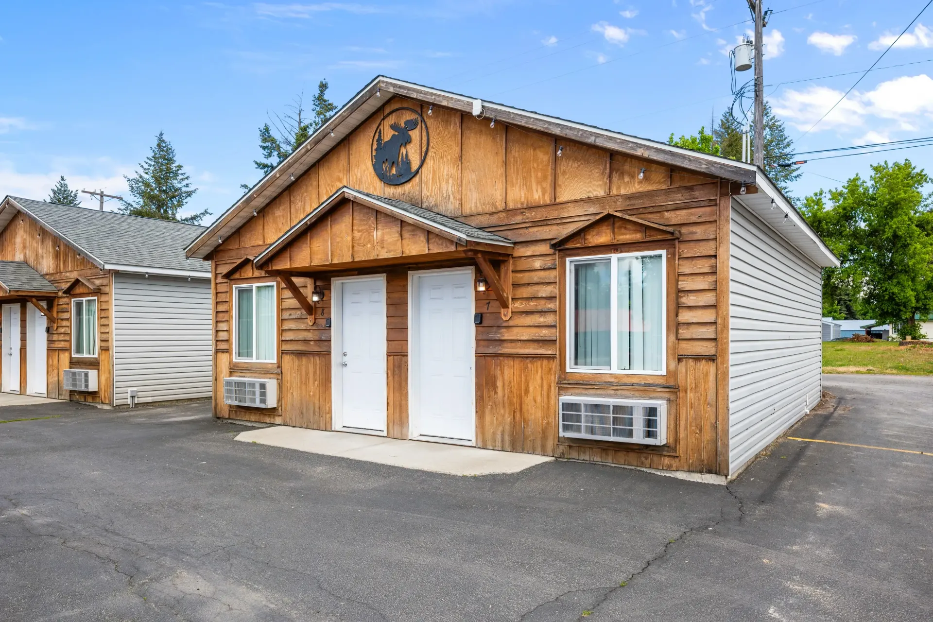 A small wooden house with white doors and windows in a parking lot.