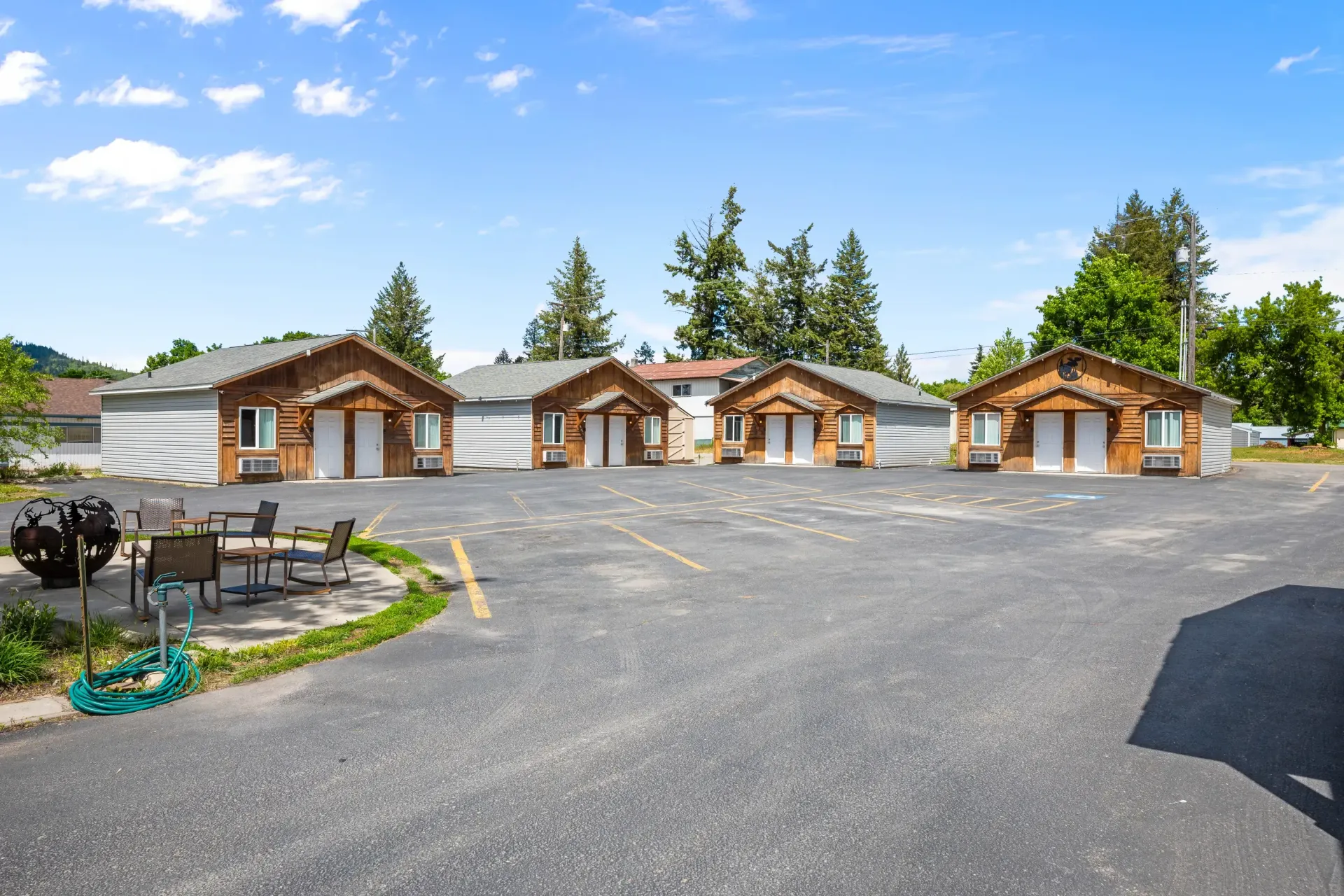 A row of motel rooms are lined up in a parking lot.