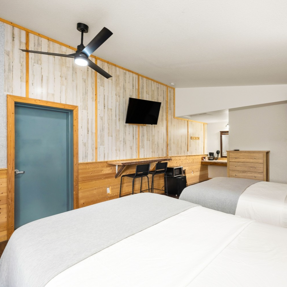 A hotel room with two beds and a ceiling fan