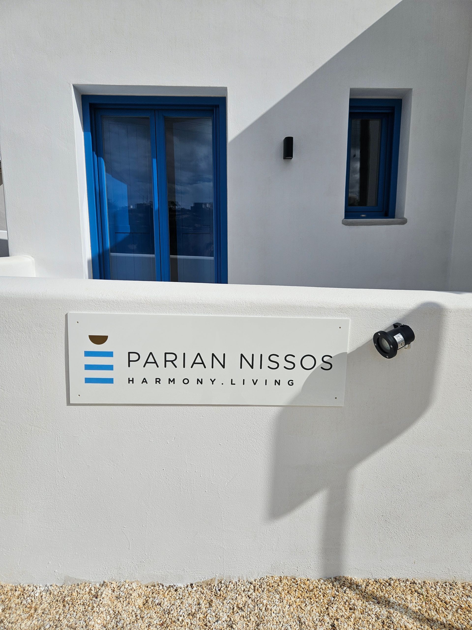 White building with blue doors and windows; sign reads 