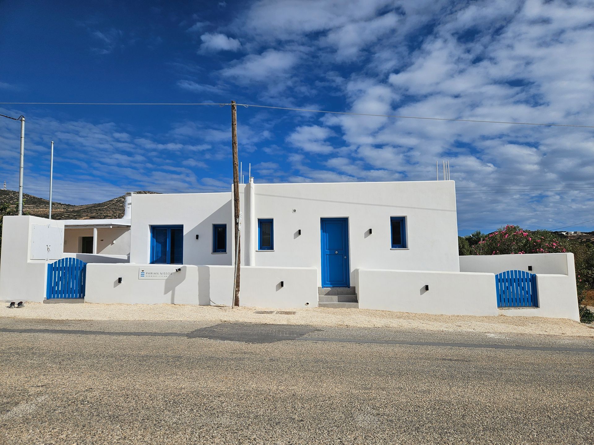 Dining table set for two, framed by blue-trimmed open doors with an outdoor view of a bright blue sky and distant buildings.