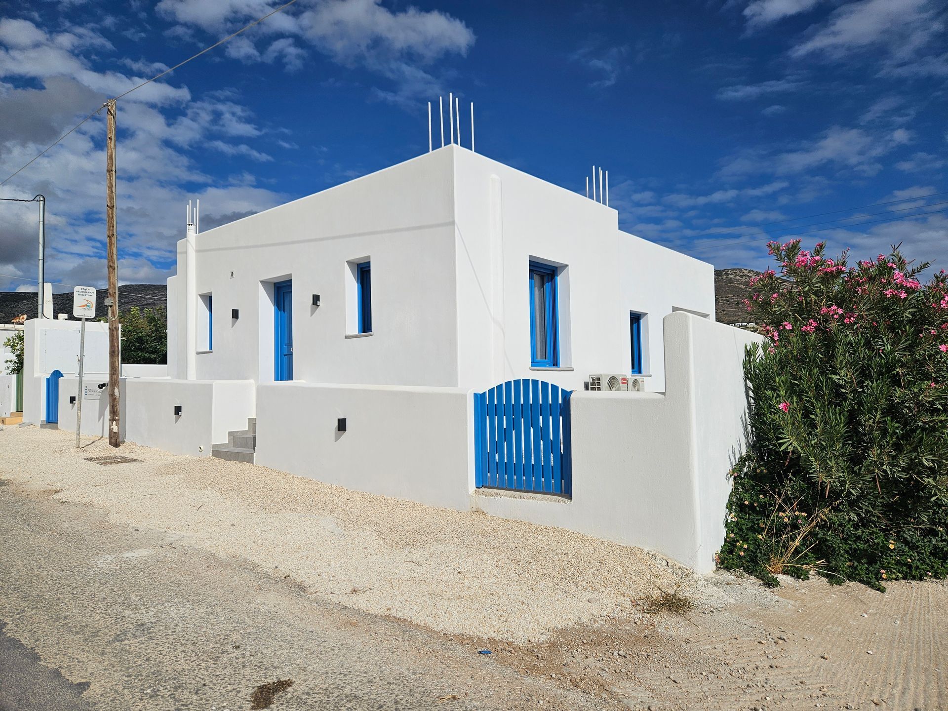 White building with blue accents and gate, set against a blue sky.