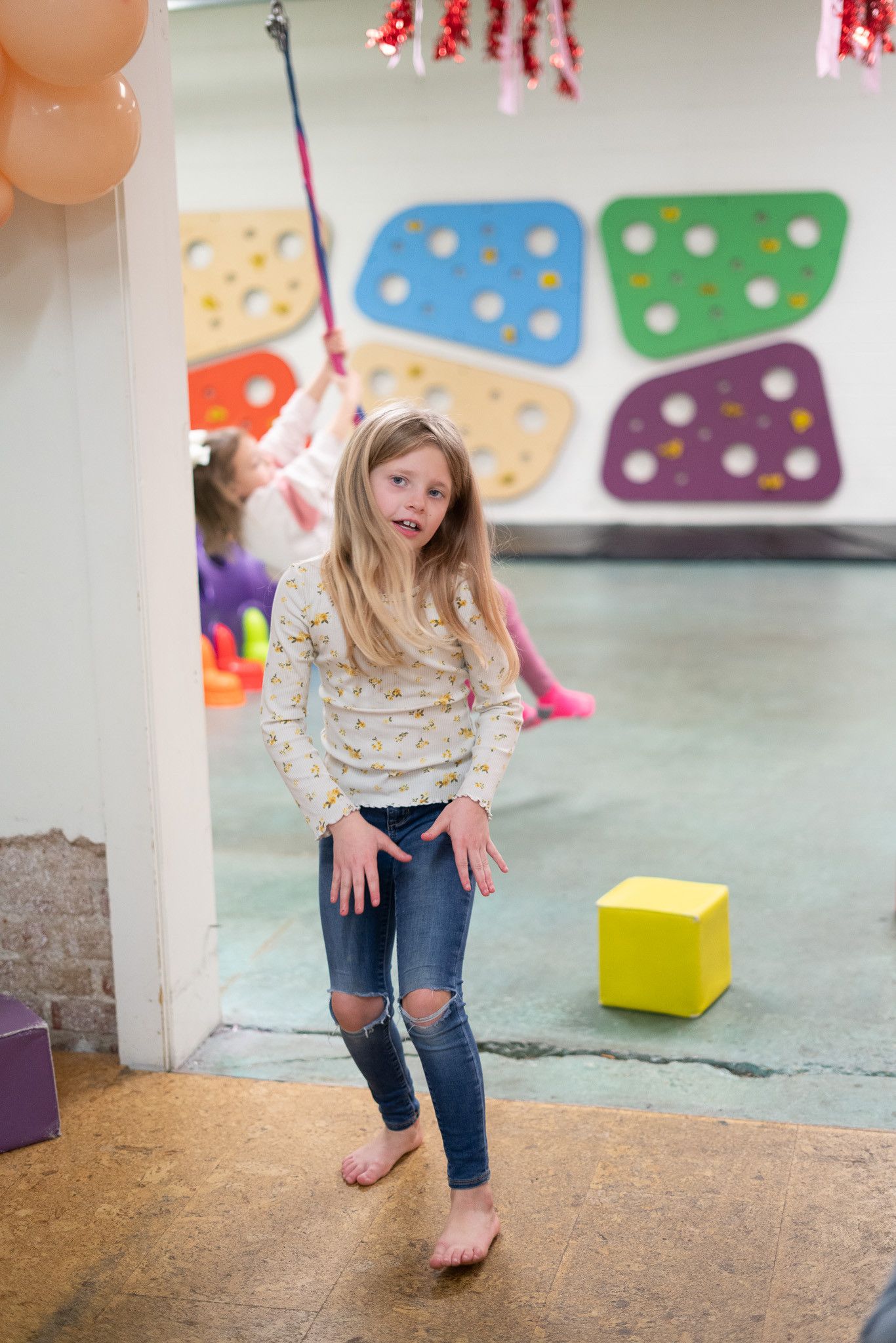 A little girl is standing in a room with balloons on the wall.