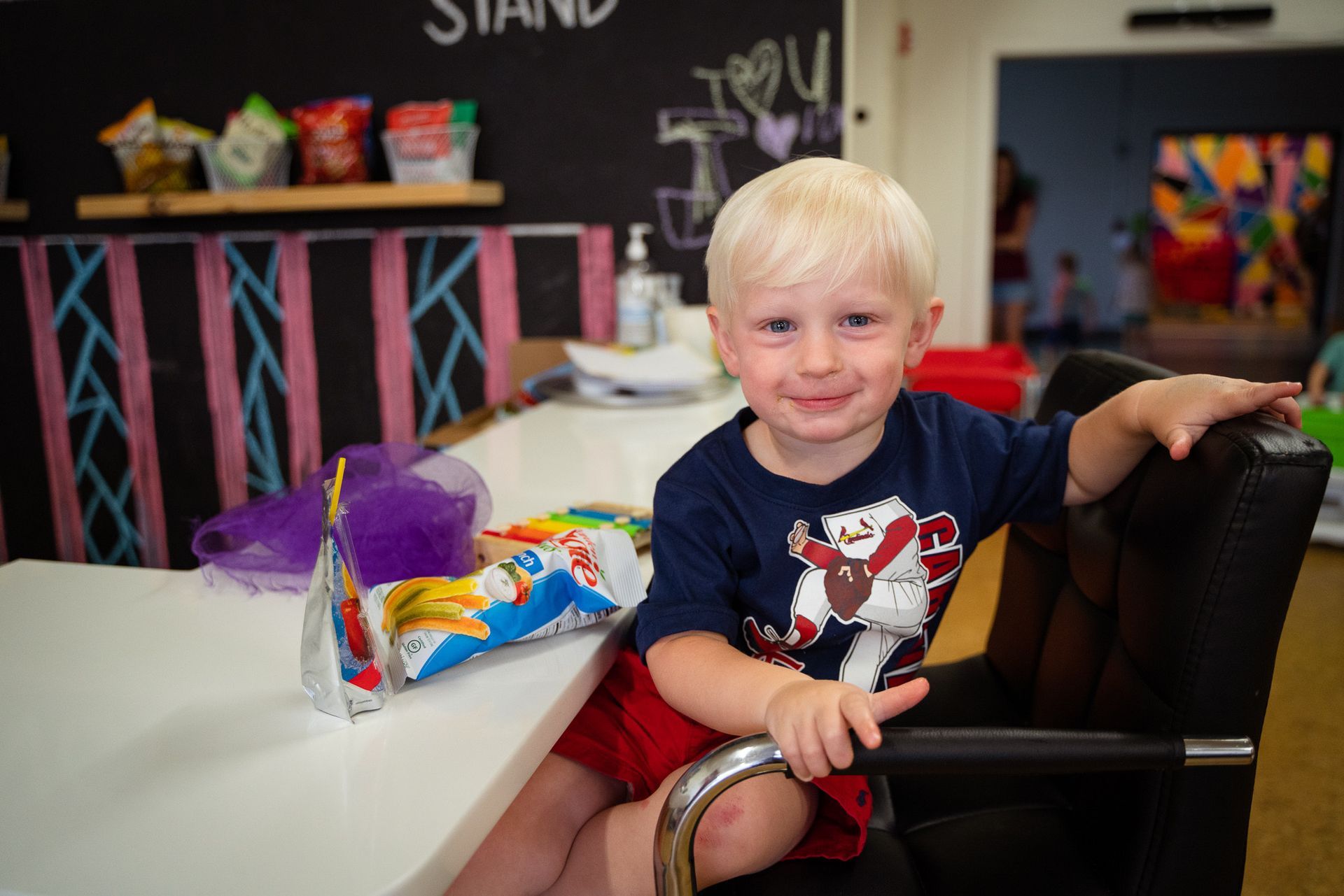 A young boy is sitting in a chair in front of a table.