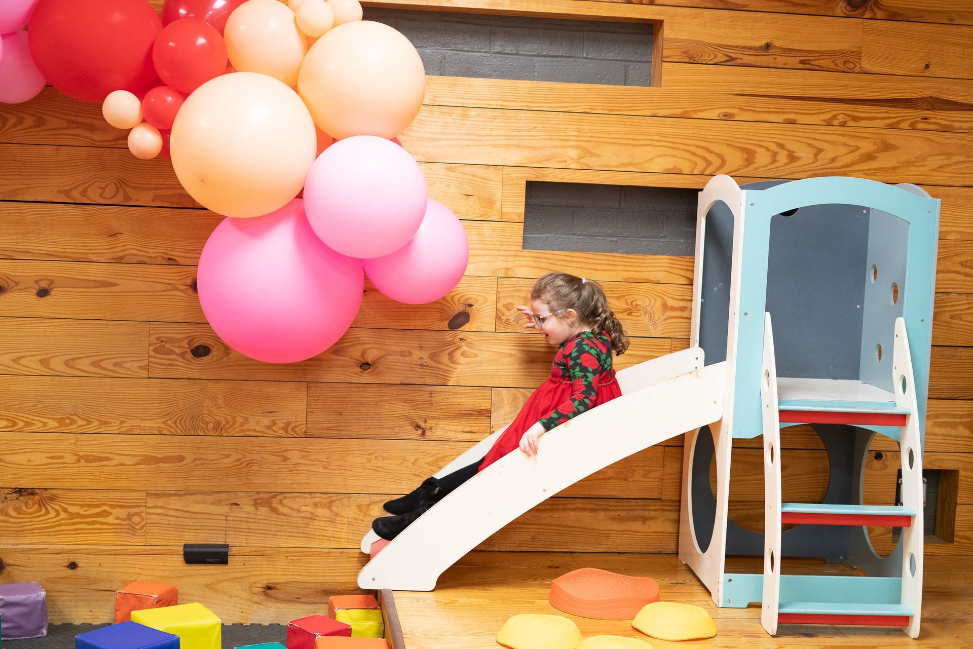 A little girl is sitting on a slide in a playground.
