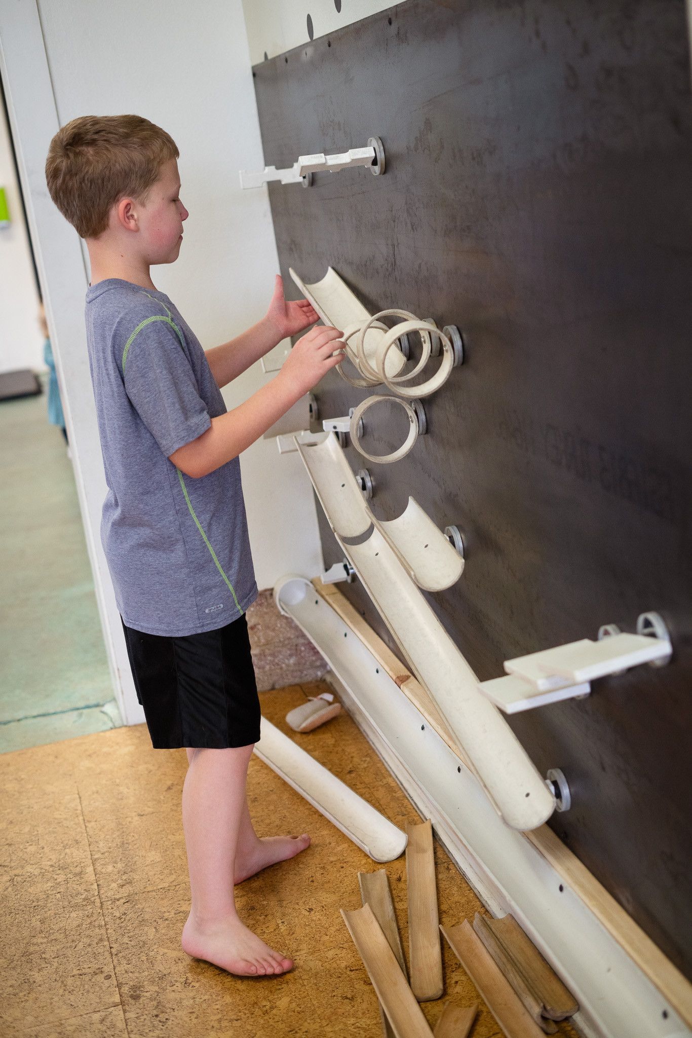 A young boy is playing with pipes on a wall.