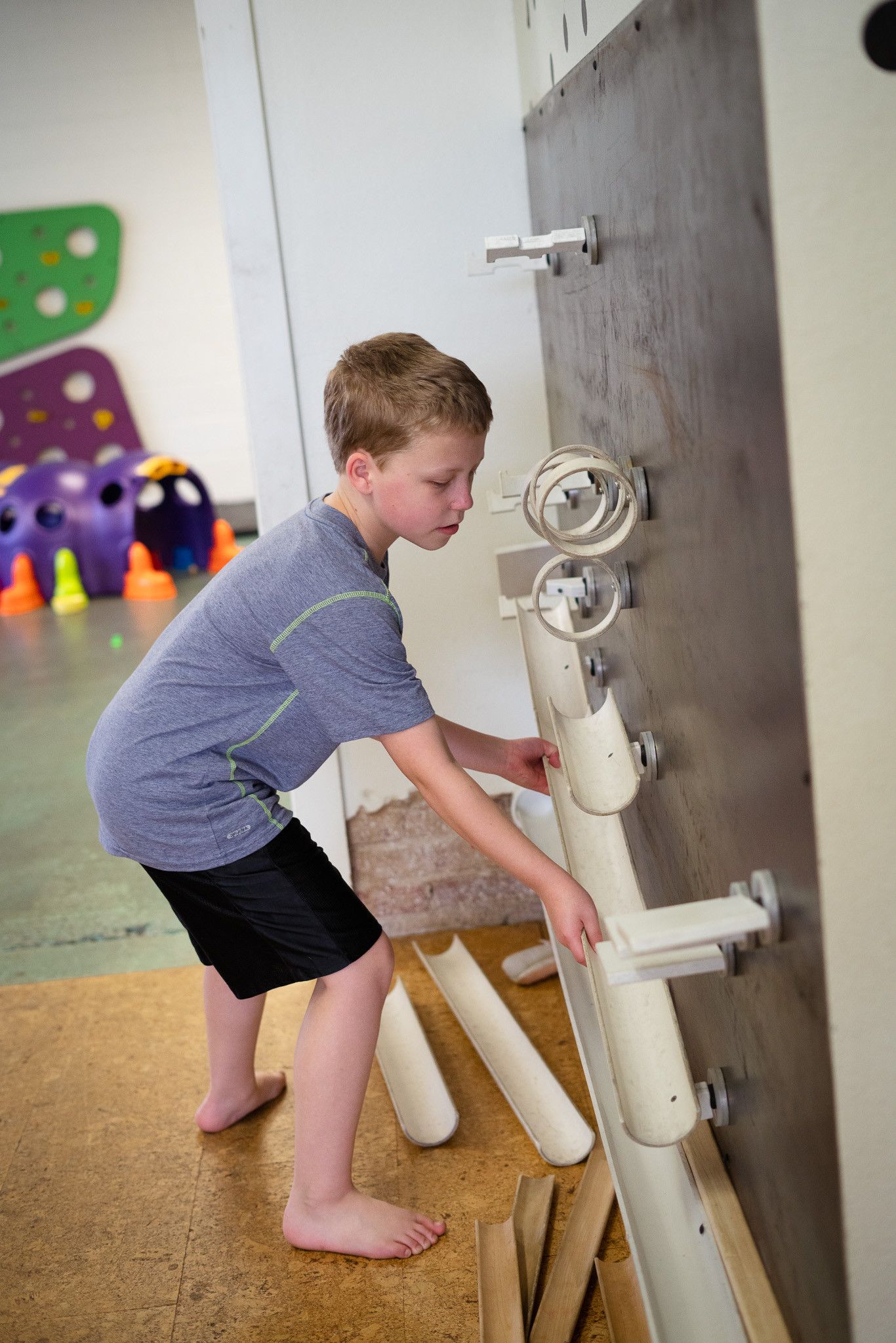 A young boy is playing with a wall made of pipes.