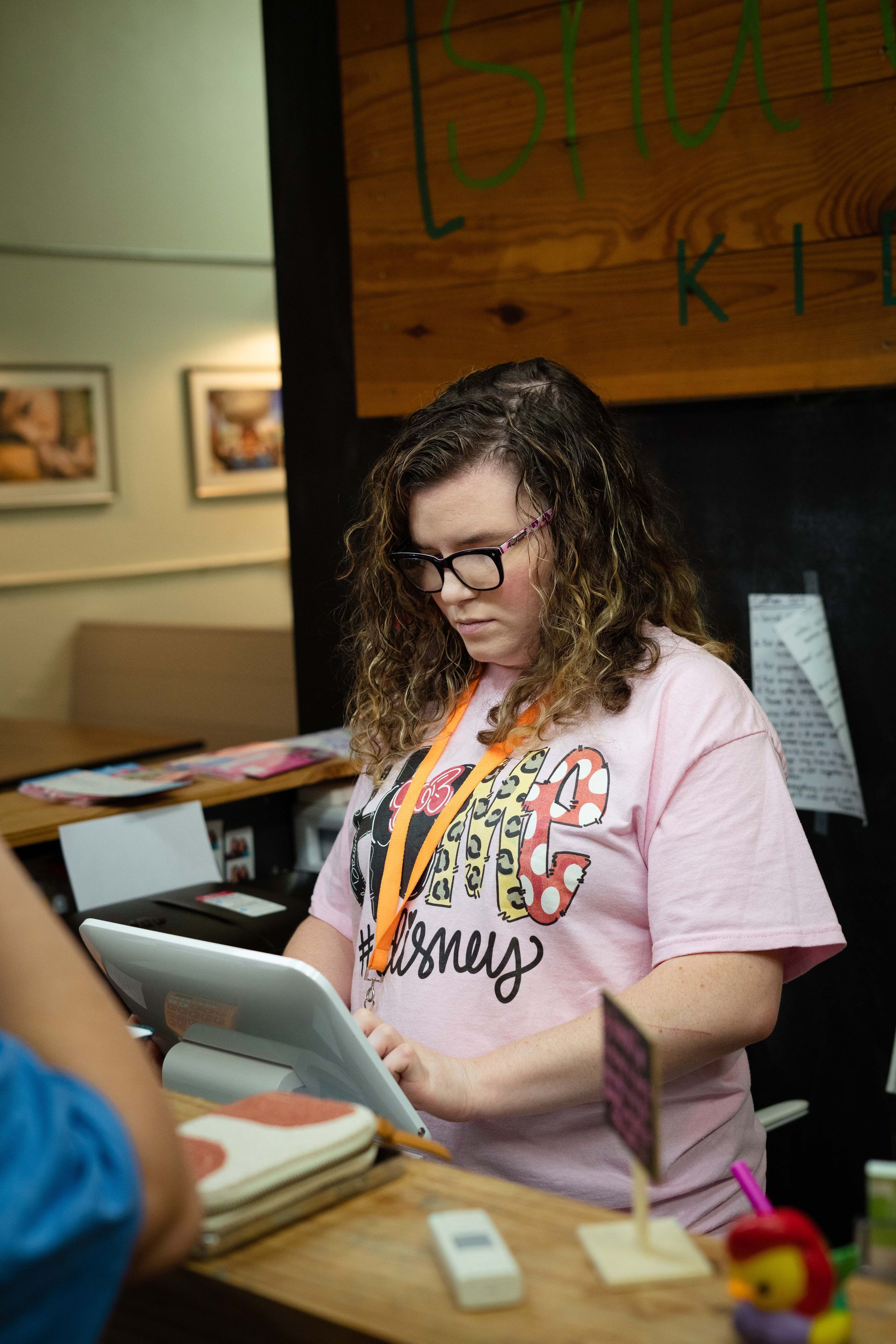 A woman in a pink shirt is using a tablet computer.