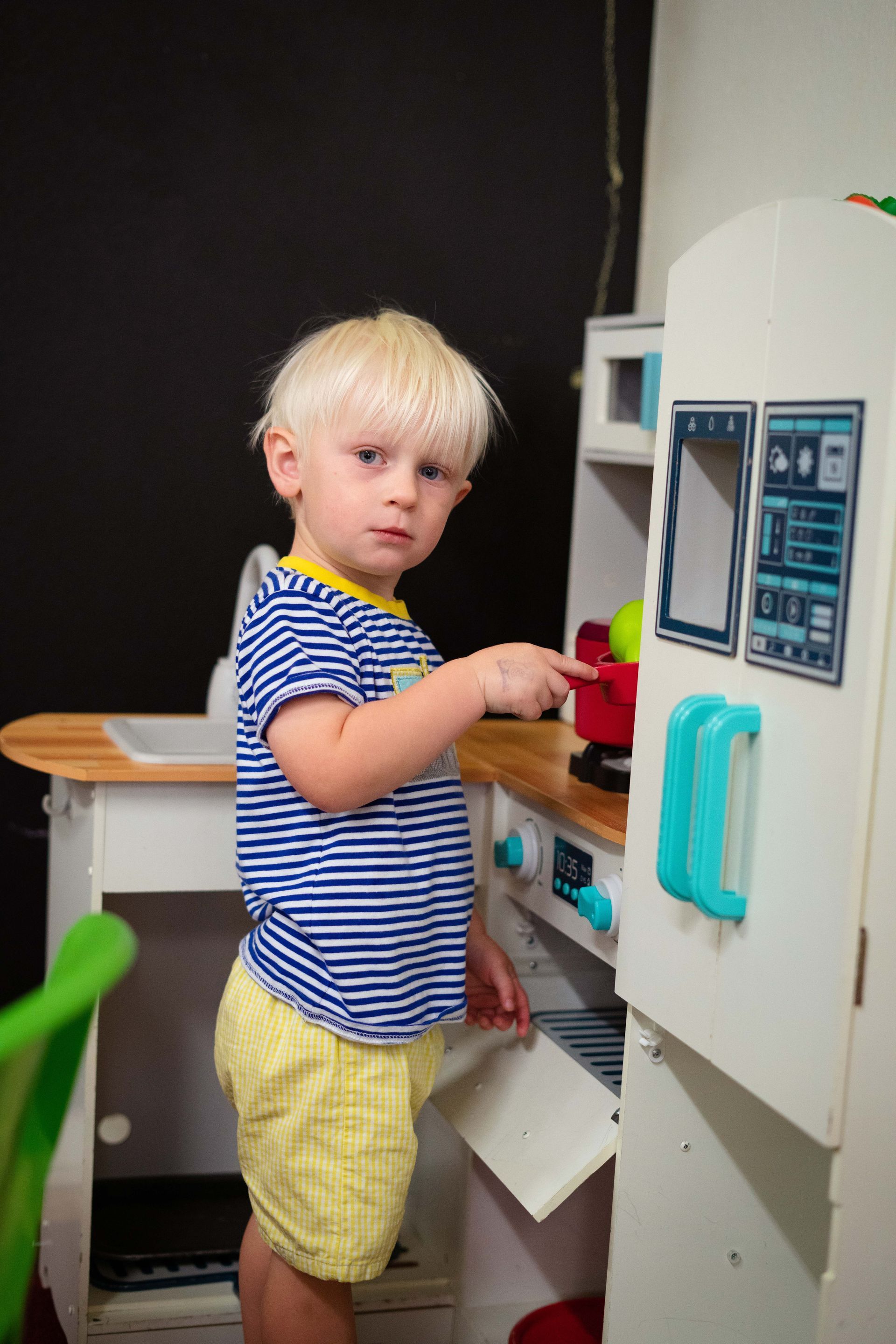 A little boy is playing in a toy kitchen.