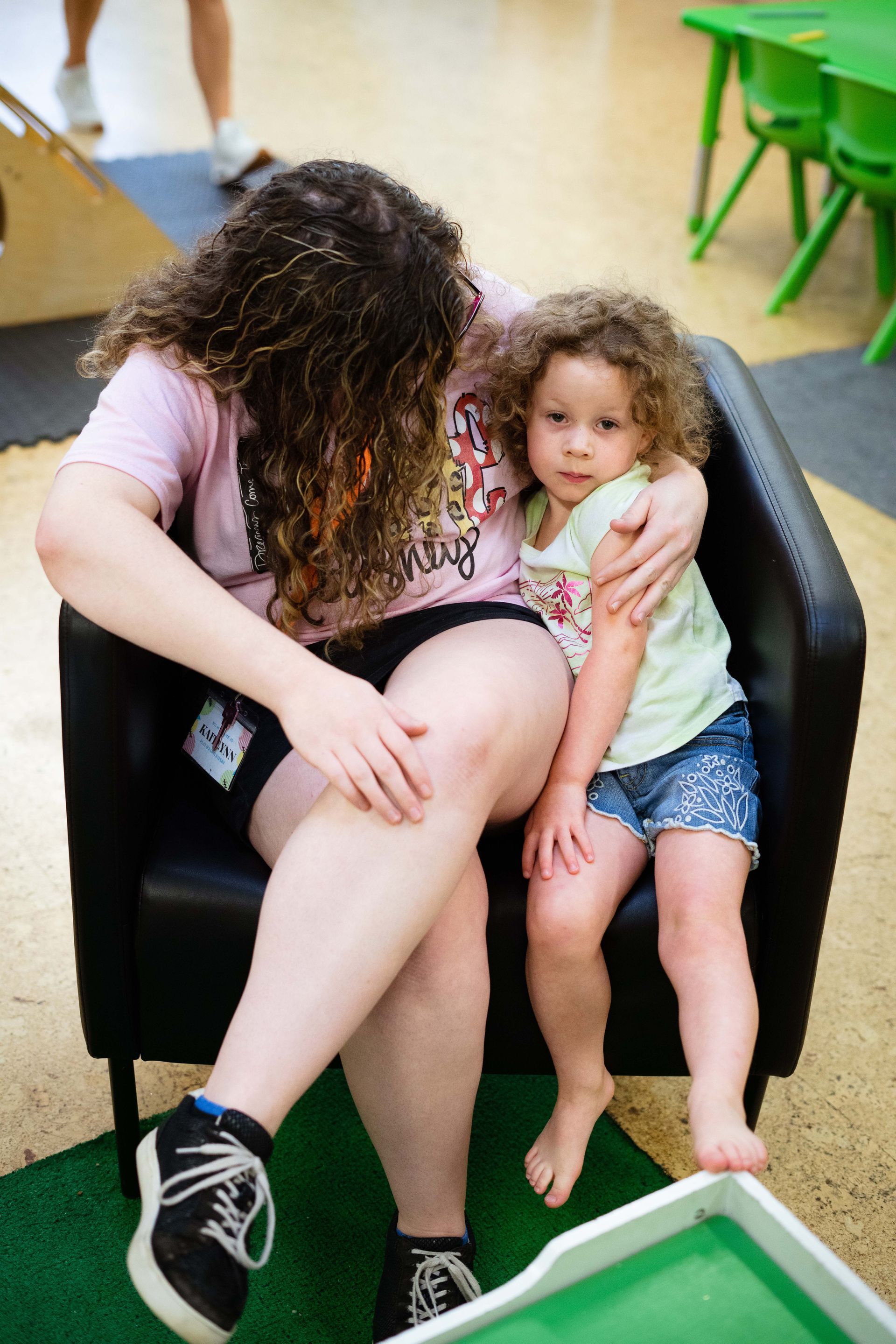 A woman is sitting in a chair with a little girl on her lap.