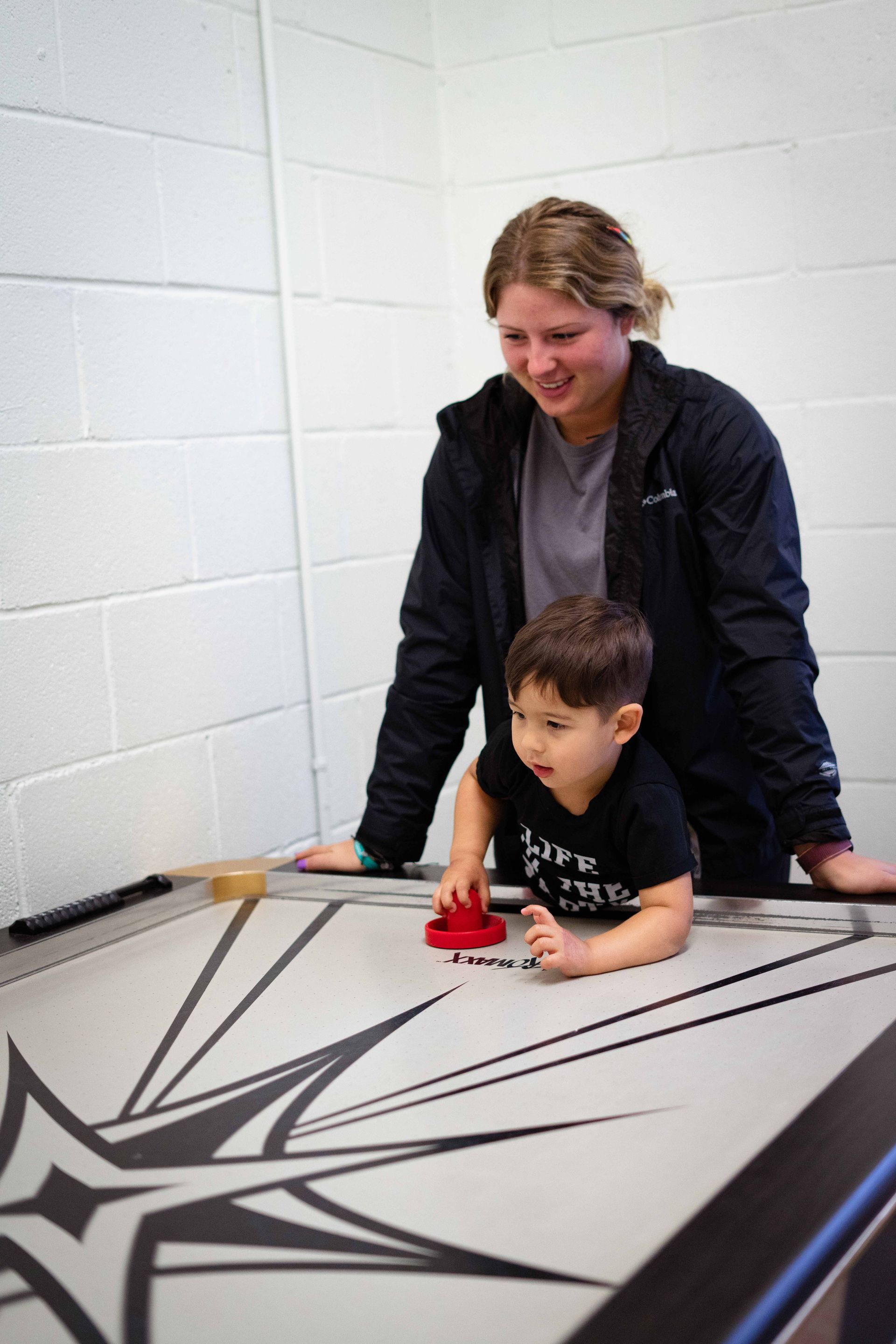 A woman and a child are playing a game of air hockey.