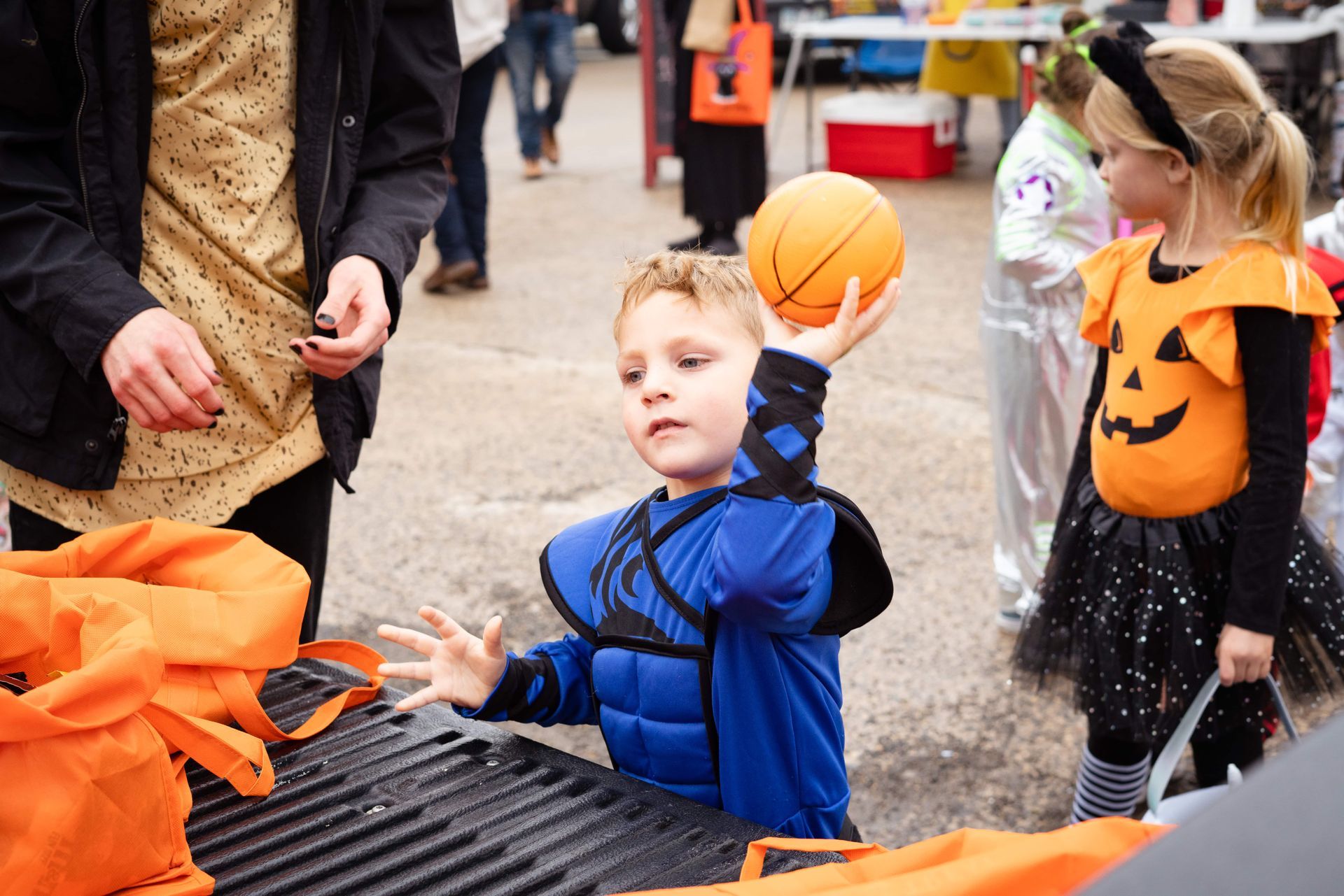A young boy in a halloween costume is holding a basketball in his hand.