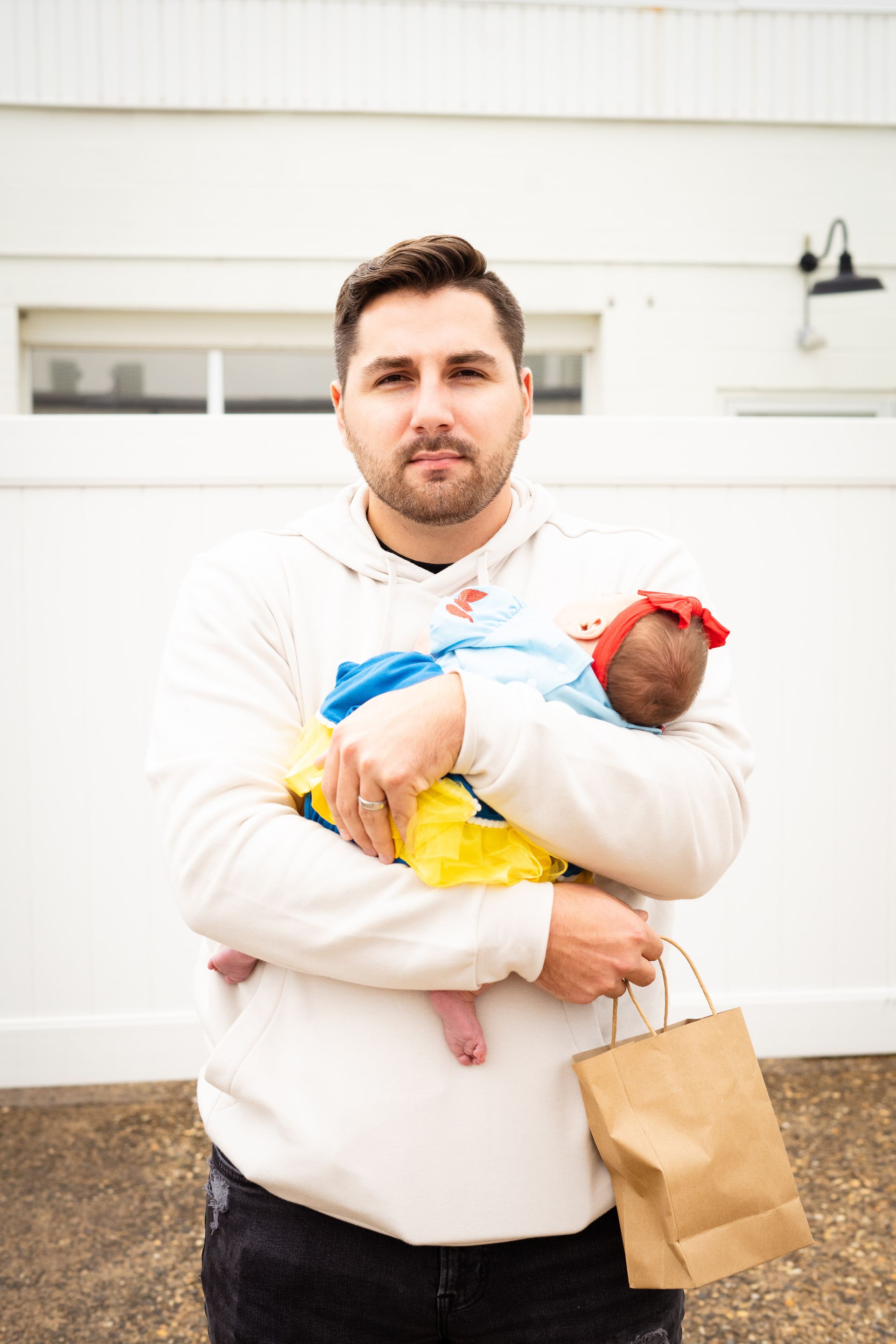 A man is holding a baby in his arms and holding a paper bag.