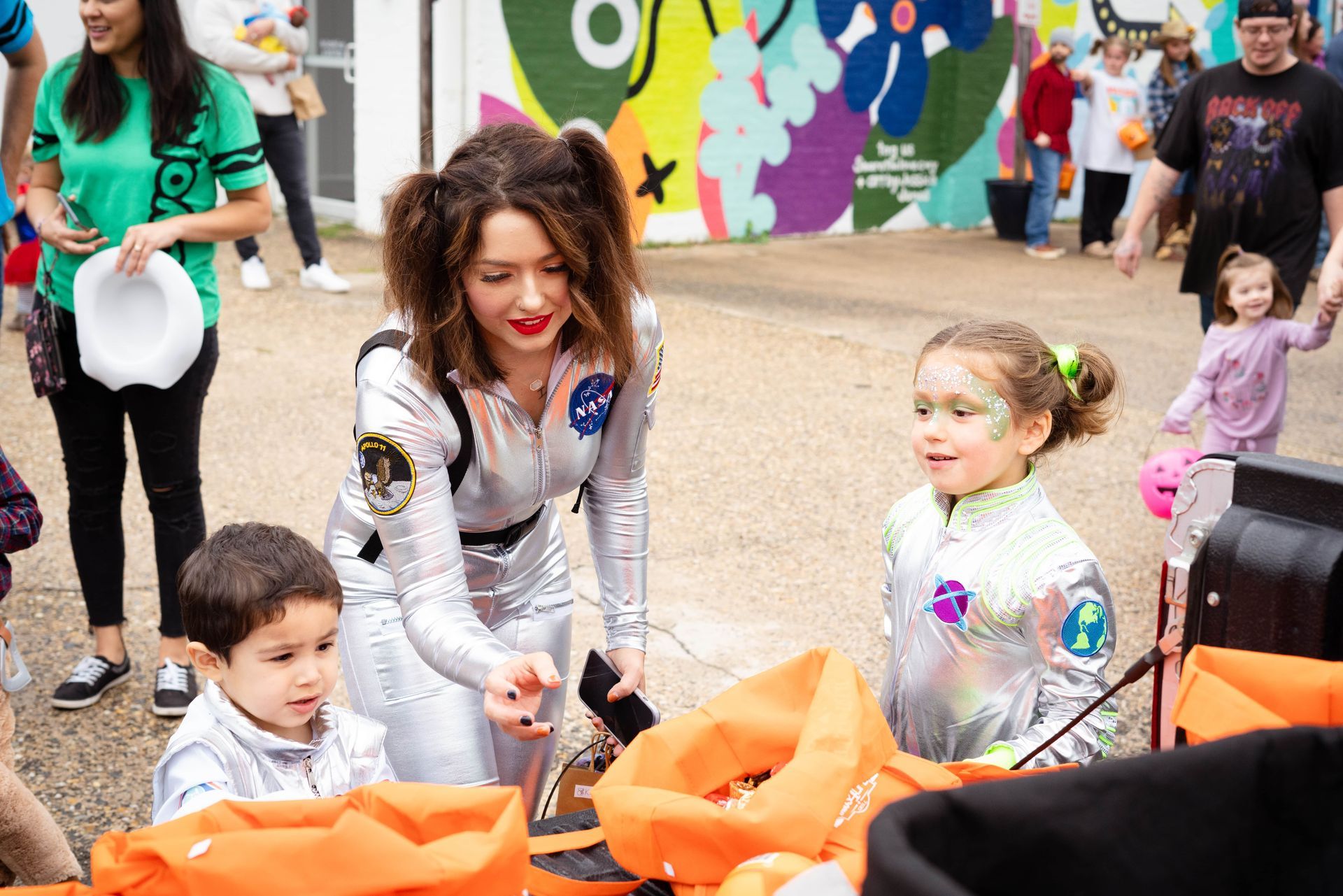 A woman in a space suit is standing next to two children.
