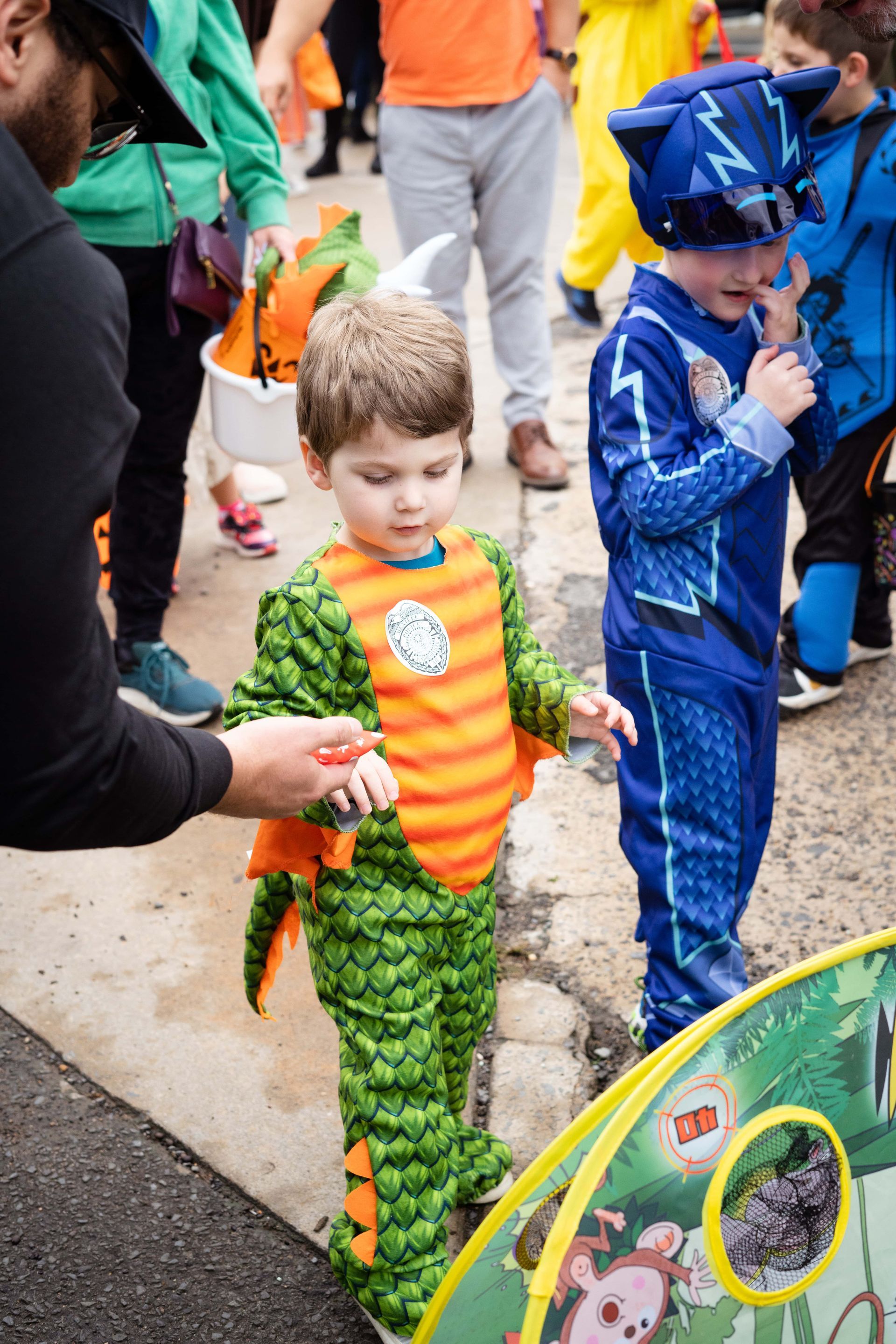 A boy in a dragon costume is standing next to a man in a cat costume.