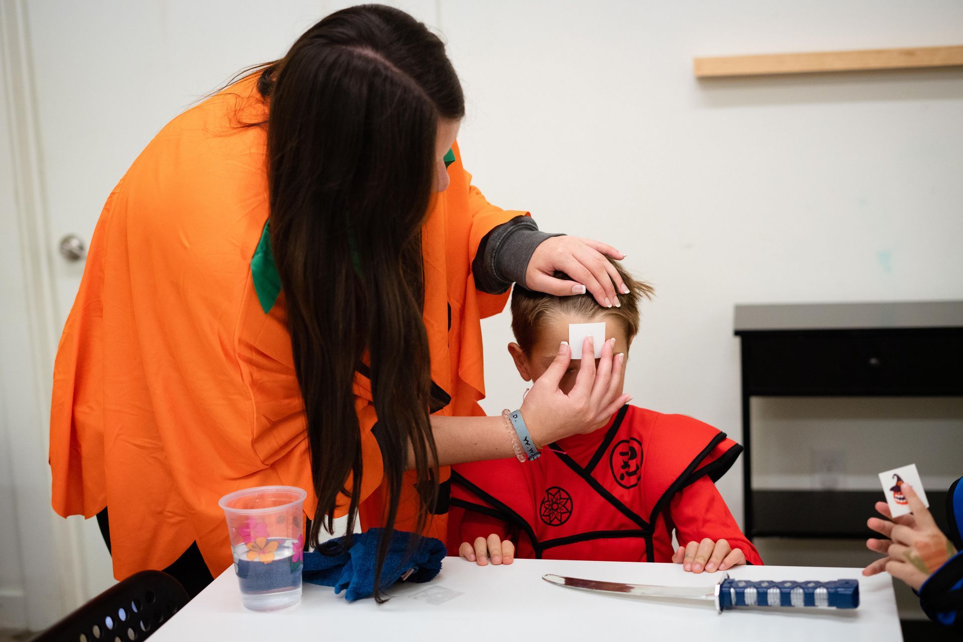 A woman is cleaning a child 's face with cotton swabs.