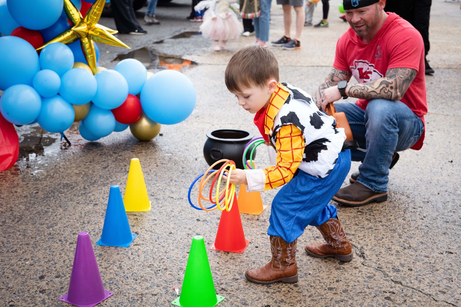 A little boy dressed as woody from toy story is playing a game with cones.