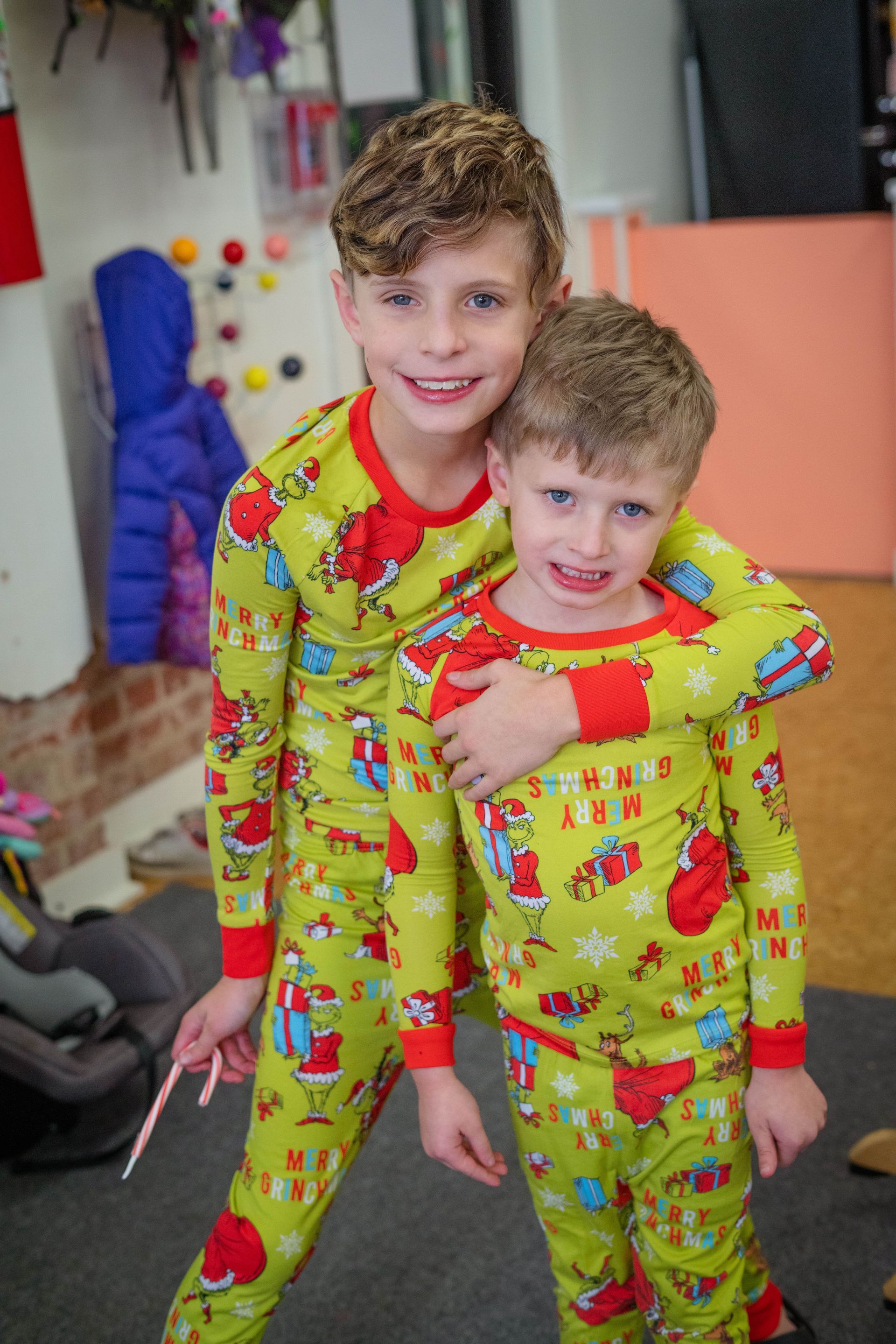 Two young boys in christmas pajamas are posing for a picture.