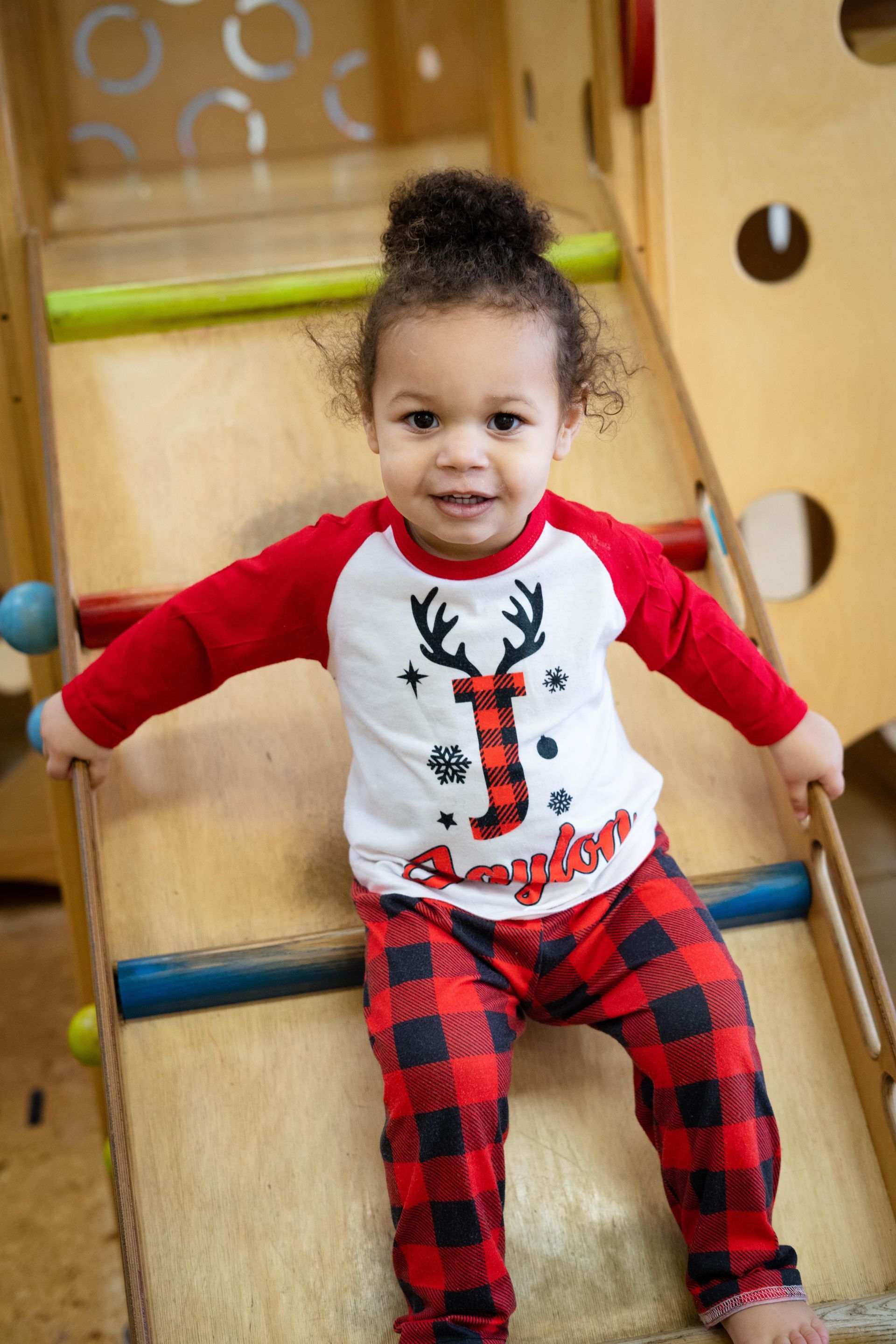 A little girl is sitting on a wooden slide.