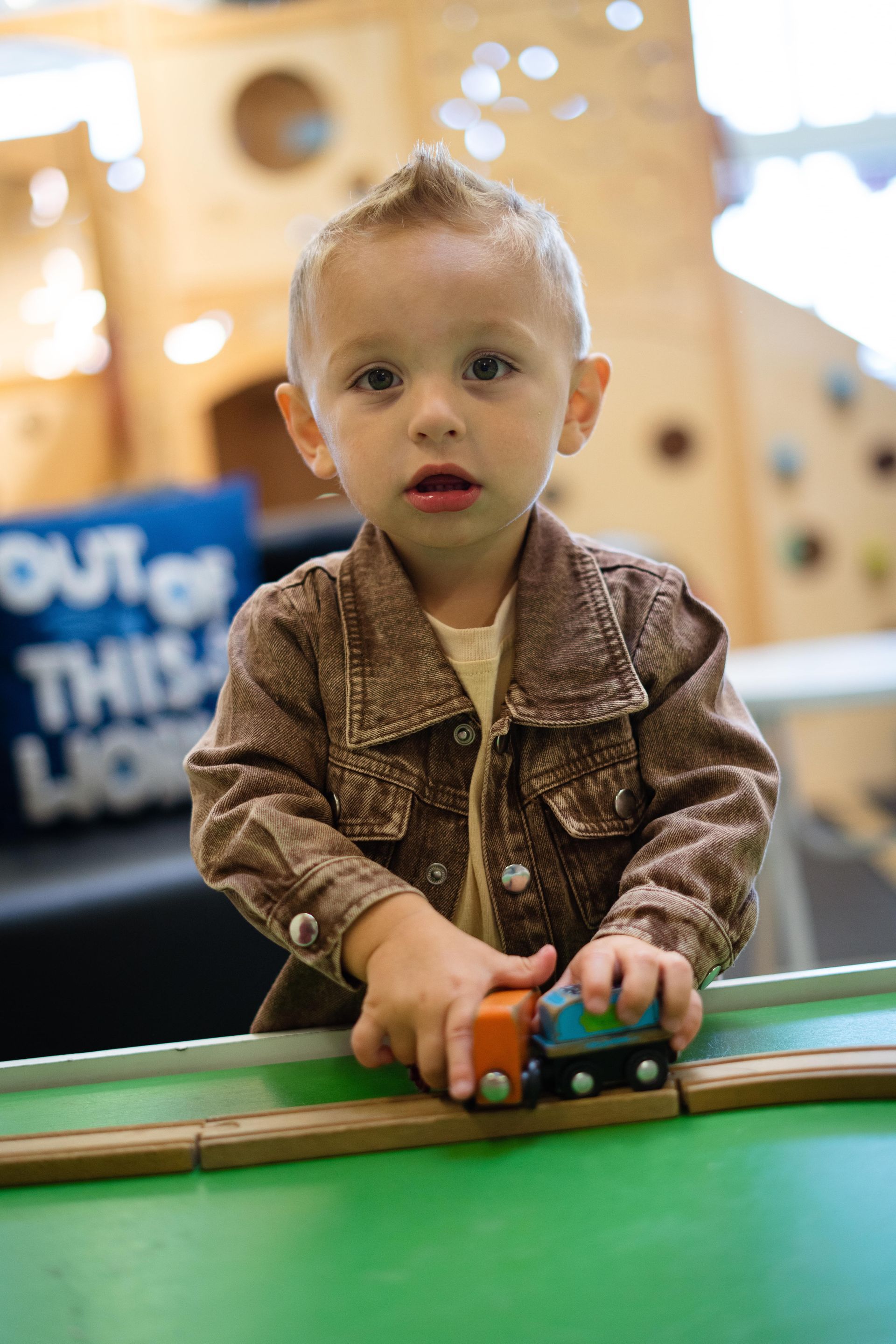 A young boy is playing with a toy train on a table.