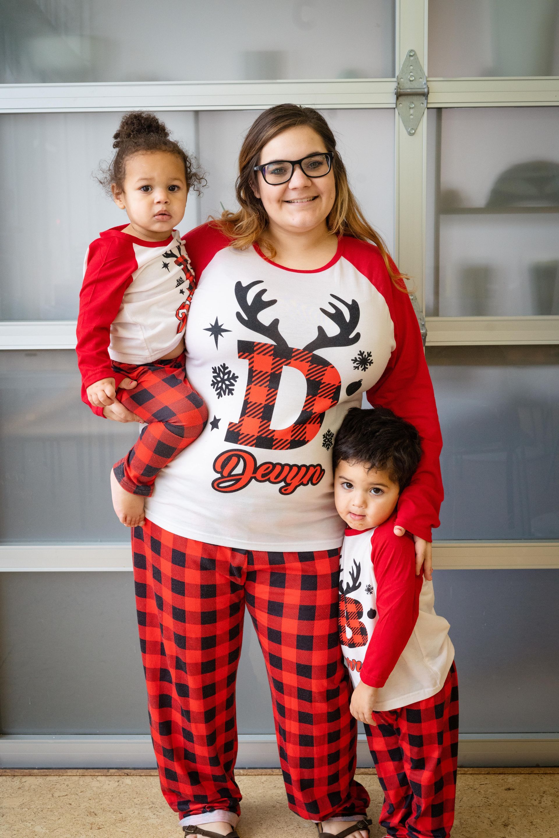 A woman is holding two children in matching pajamas.