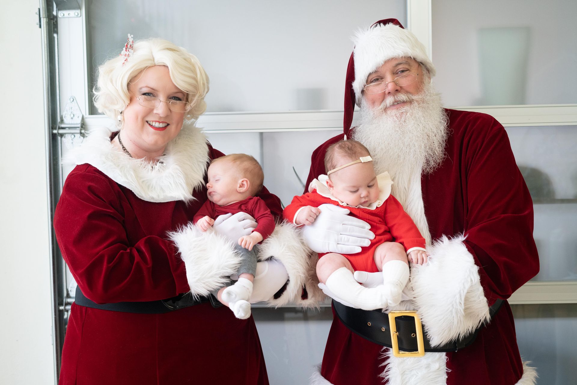 Christmas season, parents wearing Santa custom holding their toddlers.