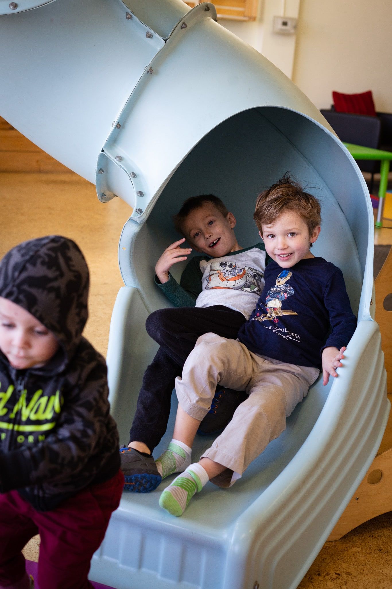 Two young boys are sitting on top of a slide.