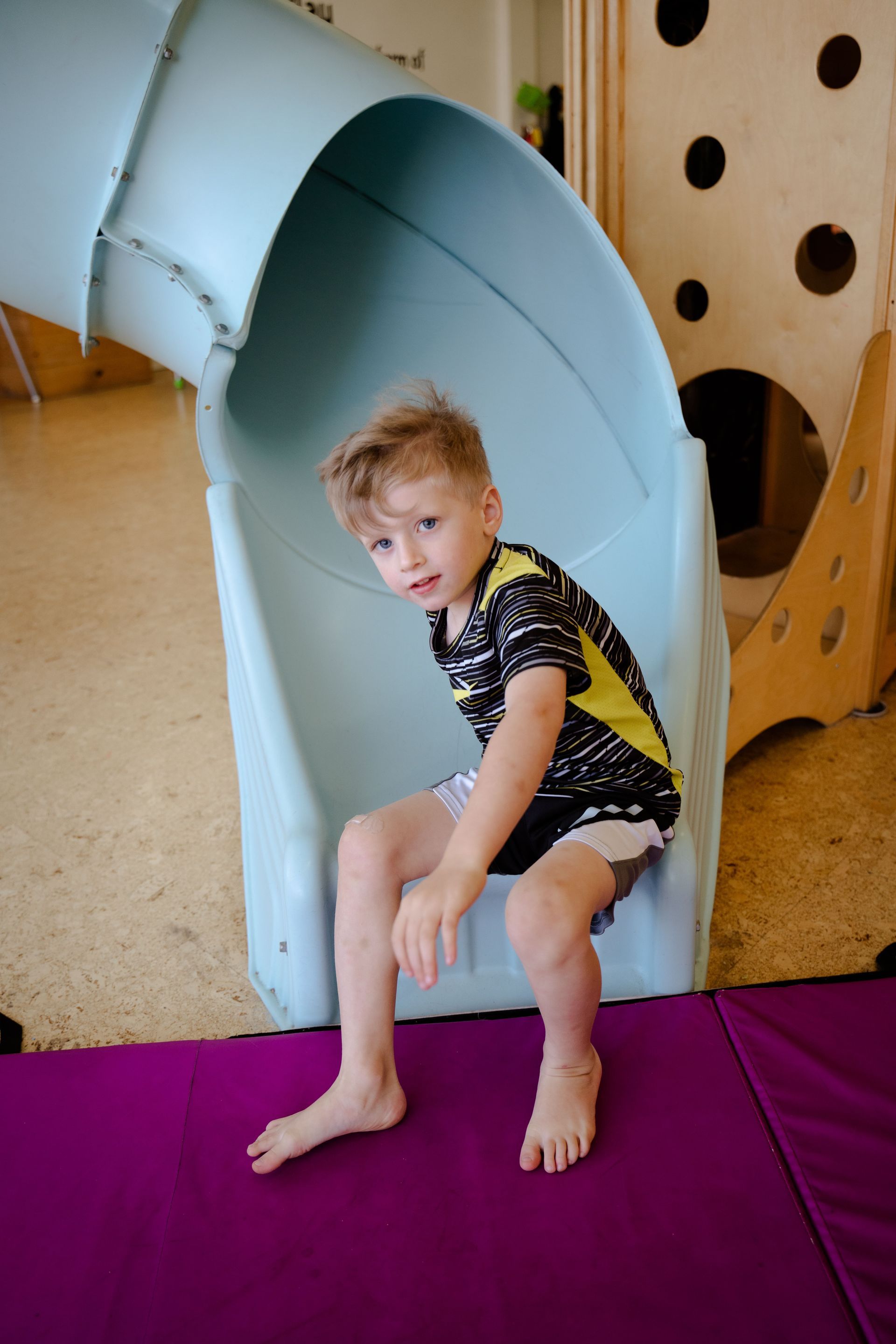Kids wearing black and yellow shirt playing on the slide