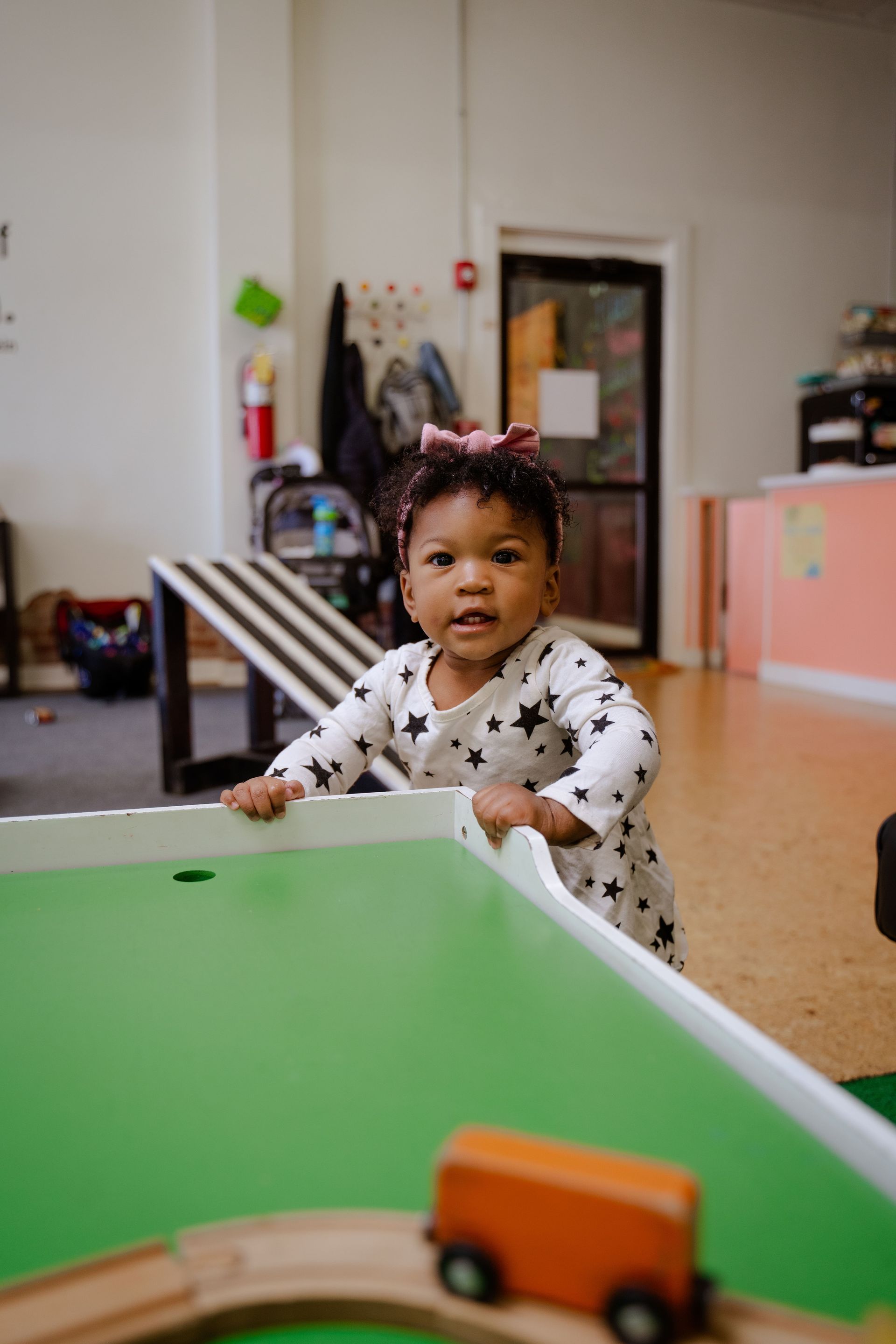 A little girl is playing with a toy train track in a room.