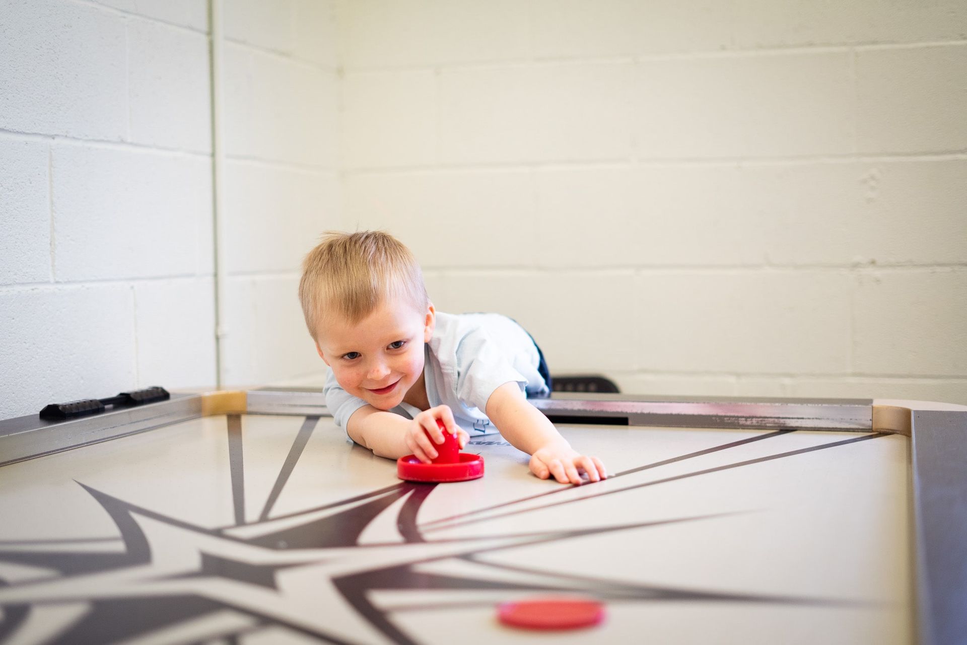 A young boy is playing air hockey on a table.