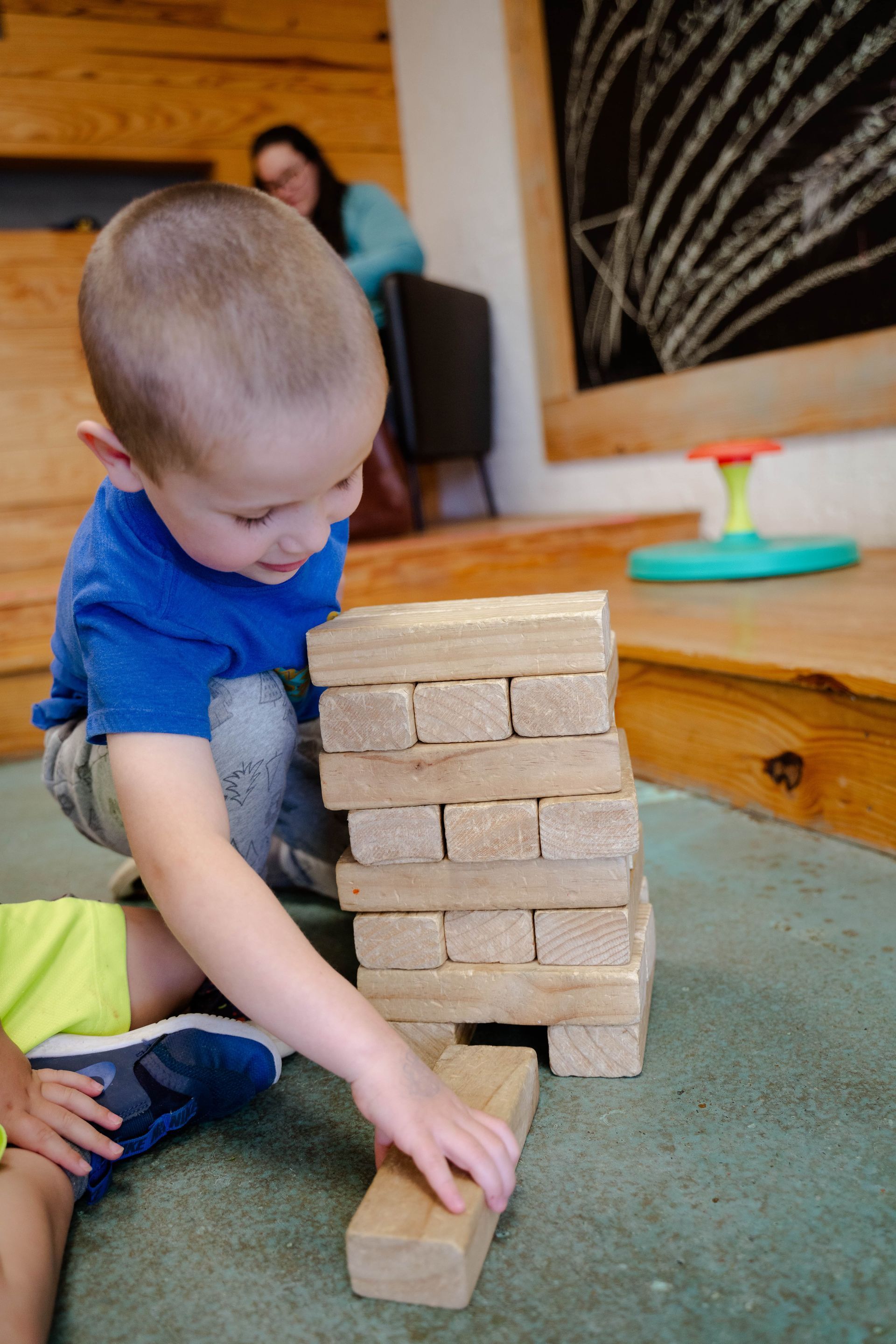 A young boy is playing with wooden blocks on the floor.