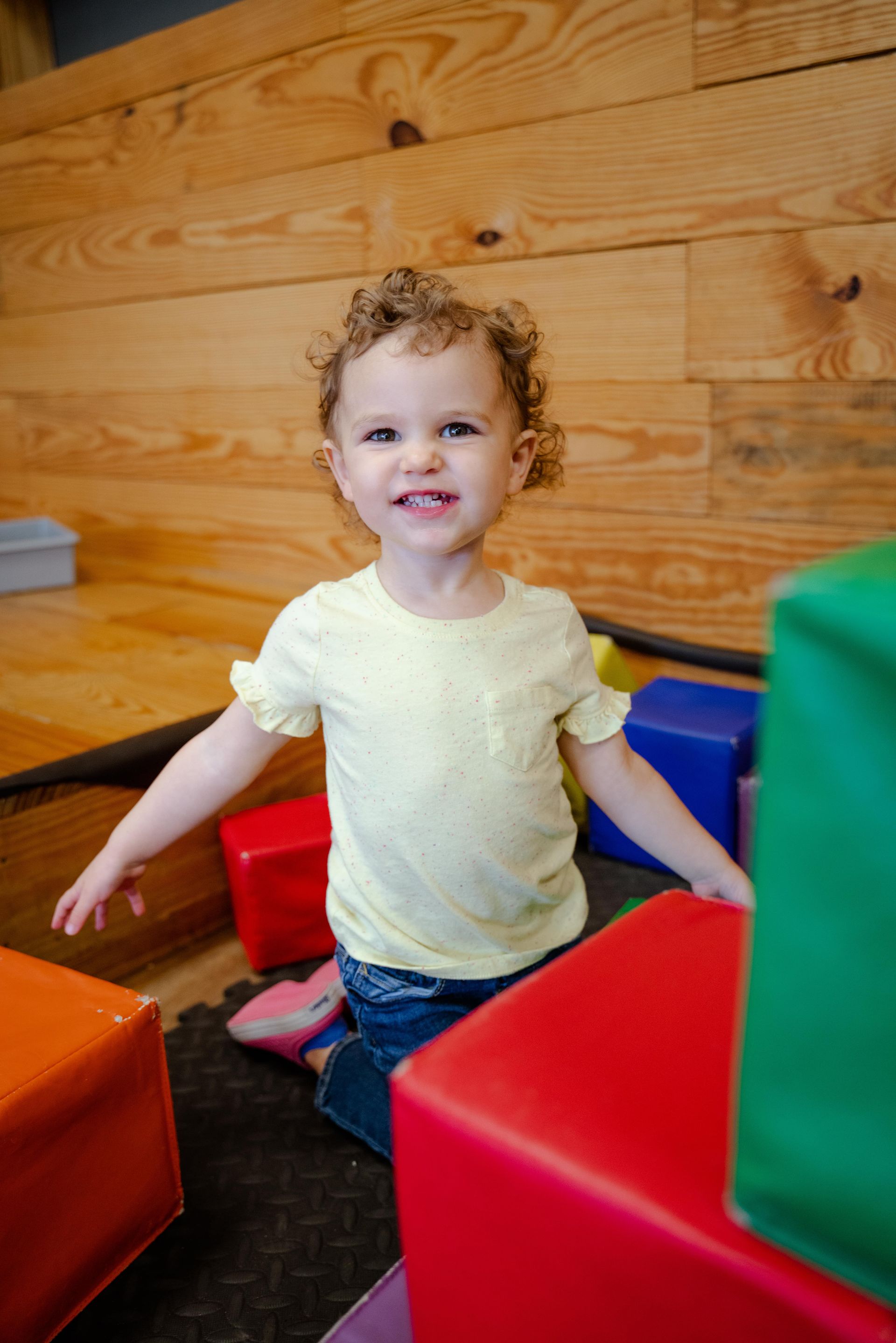 A little girl is playing with soft blocks in a room.