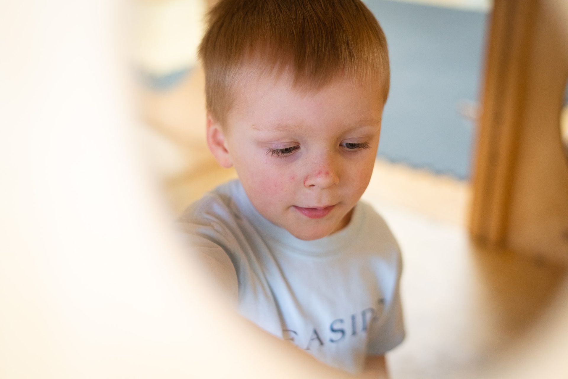 A young boy wearing a casio shirt is looking down.