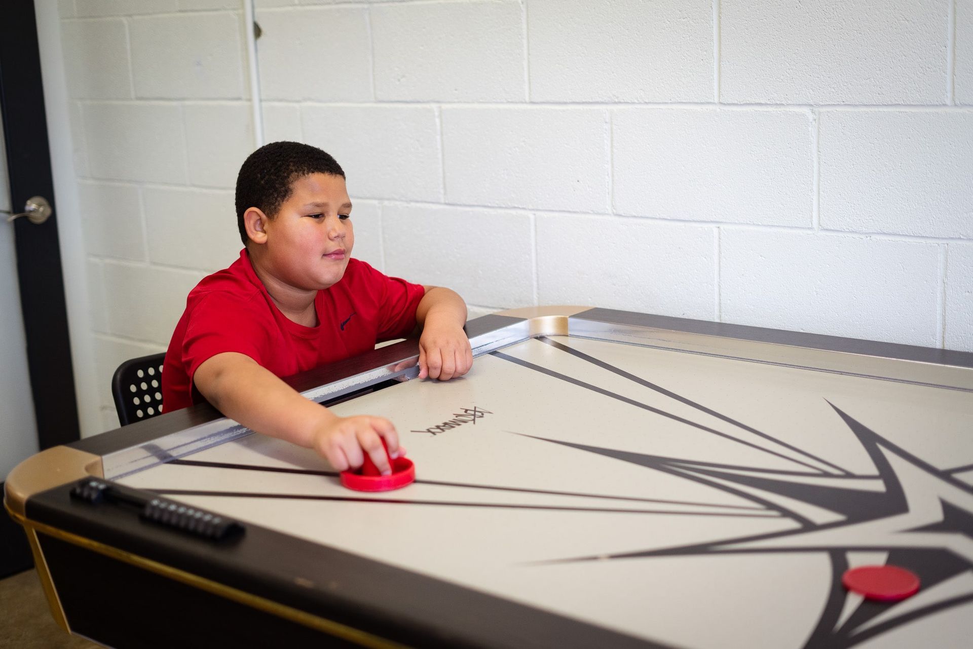 A young boy is playing air hockey on a table.