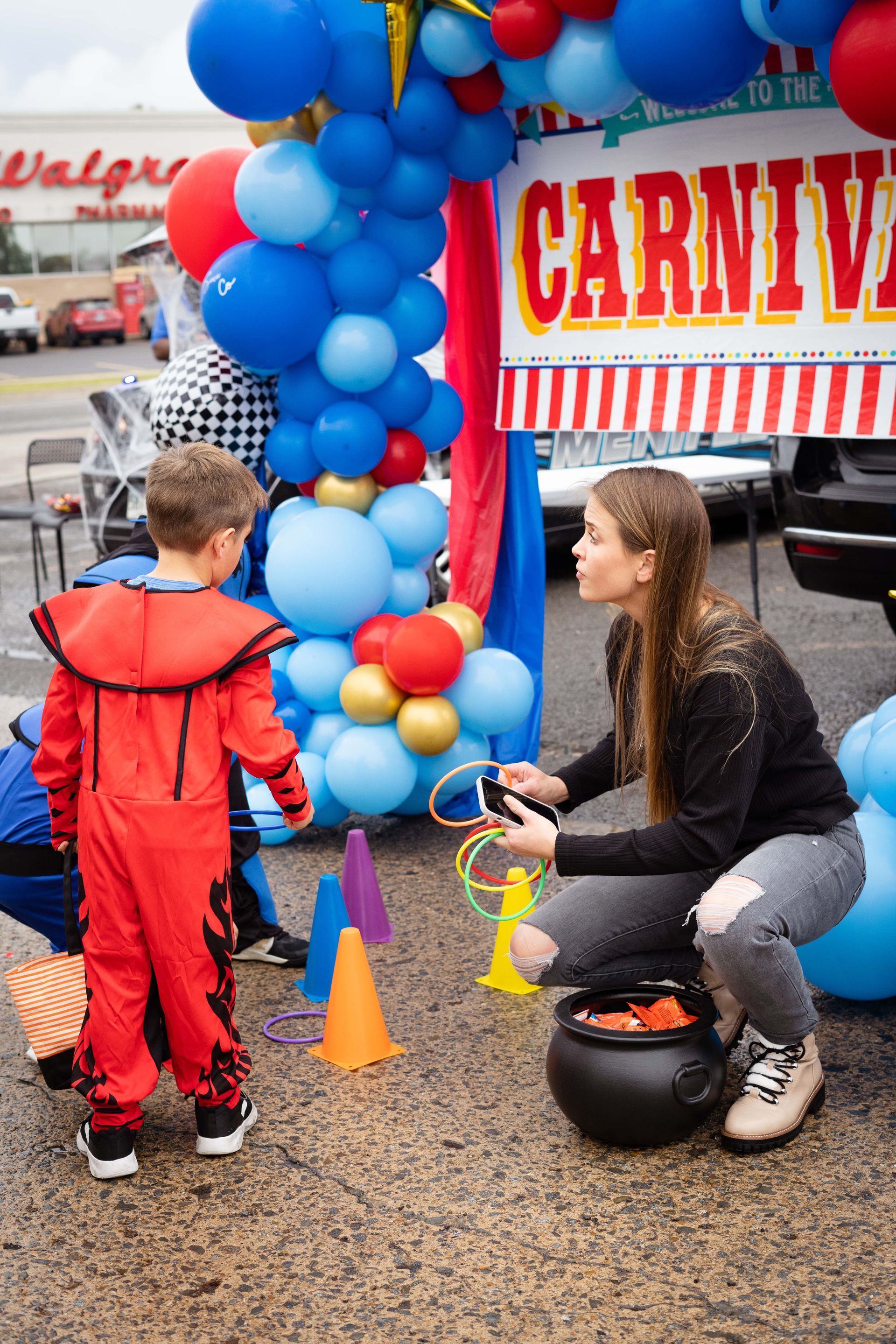 A woman is kneeling down next to a boy in a carnival costume.