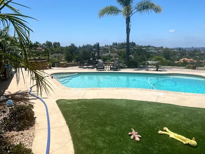 Resort pool with turquoise water, palm trees, and lounge chairs under a clear blue sky