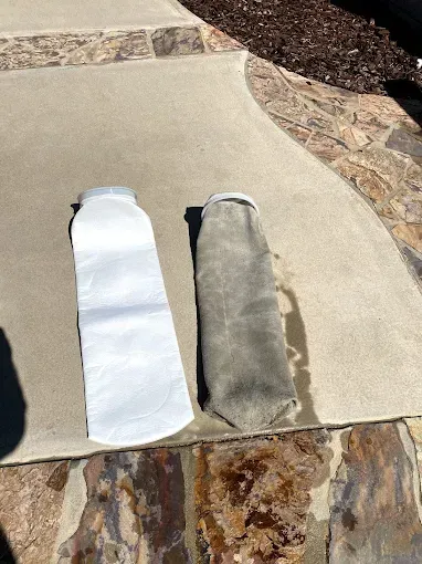 Two long white and gray fabric strips laid on a concrete patio beside stone edging