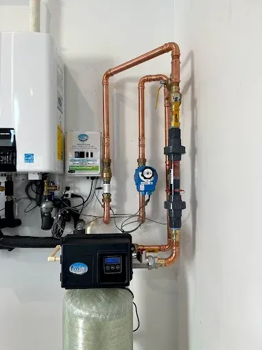 Wall-mounted water heater and copper plumbing above a water softener in a utility room