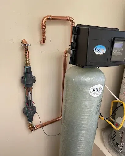 Water softener system with copper plumbing and black control unit in a utility room