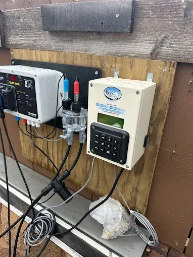 Mounted electrical control equipment on a wooden wall with cables and a keypad panel