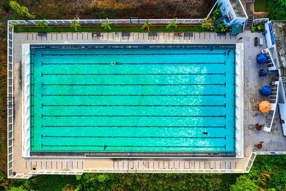 Aerial view of a turquoise outdoor lap pool with lane lines and surrounding deck.