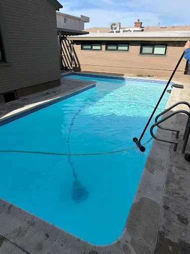 Empty blue swimming pool between apartment buildings under a clear sky