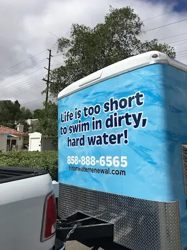 Blue trailer with slogan “Life is too short to swim in dirty, hard water” and a phone number for water treatment.