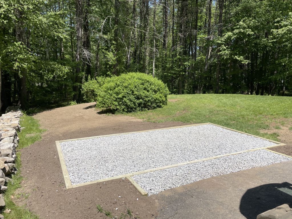Soccer ball on gravel next to a brick wall. Sunny outdoor setting.