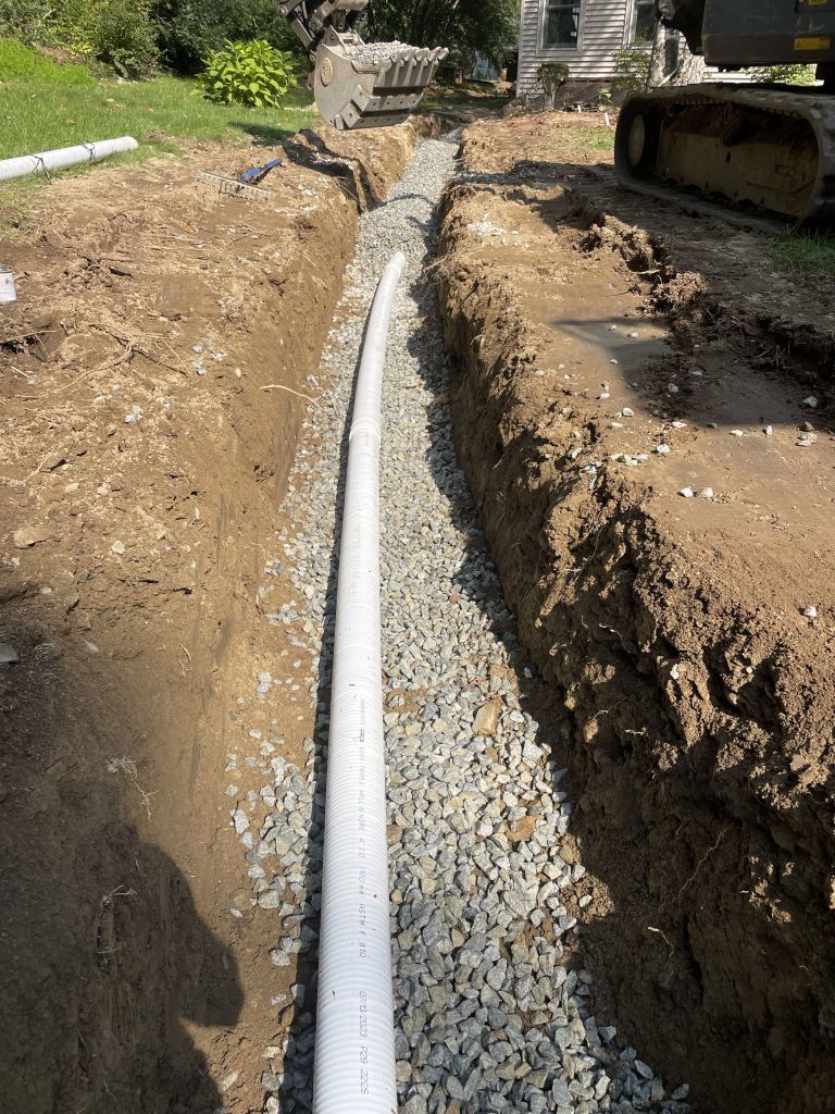Stone steps lead up to a beige house with a brown roof. An American flag flies.