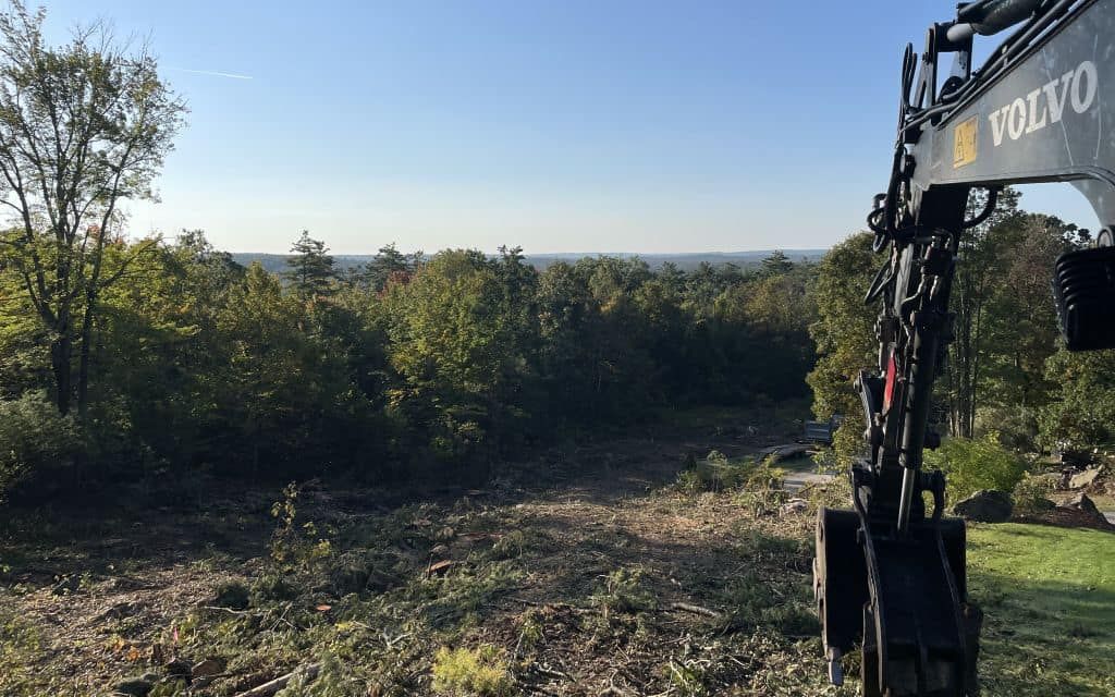 Construction site with two buildings. Gray structures, dirt, debris, and open space.