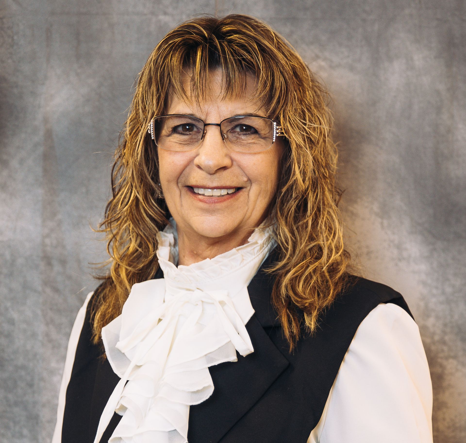 A woman wearing earrings and a blue shirt is smiling for the camera.