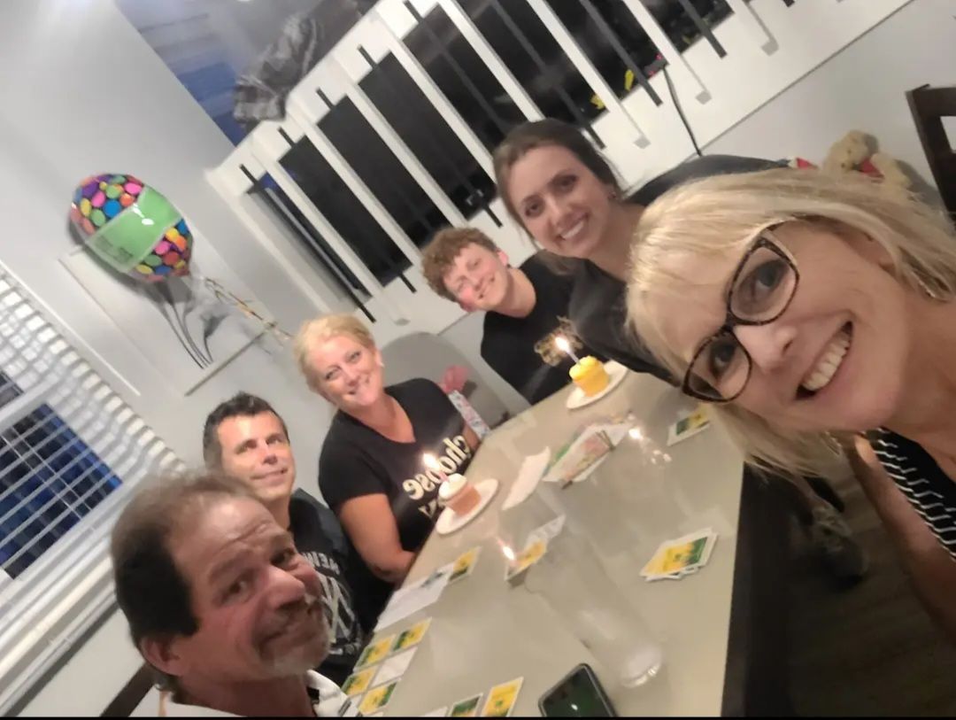 A group of people sitting around a table with a balloon in the background.