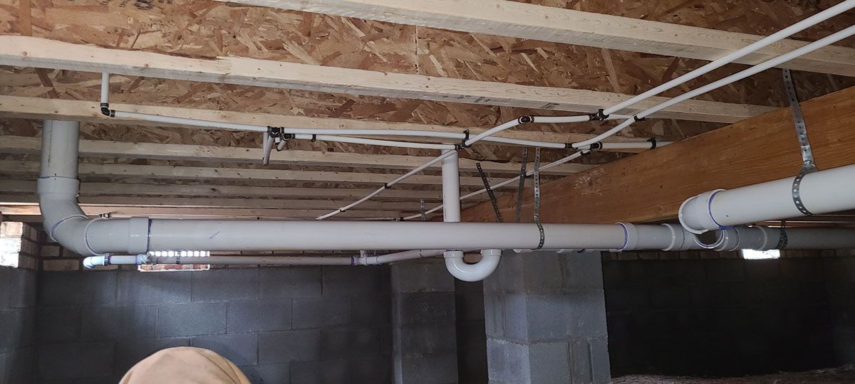 A basement with a lot of pipes and wires hanging from the ceiling.