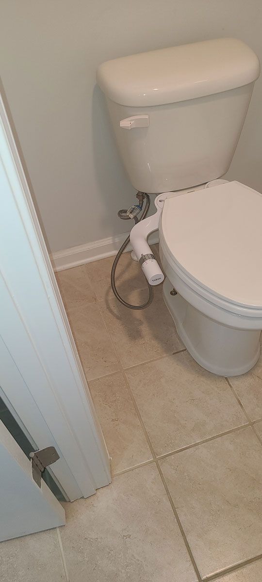 A toilet with a bidet attached to it is in a bathroom next to a door.